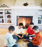 family of boys playing cards in front of a fireplace